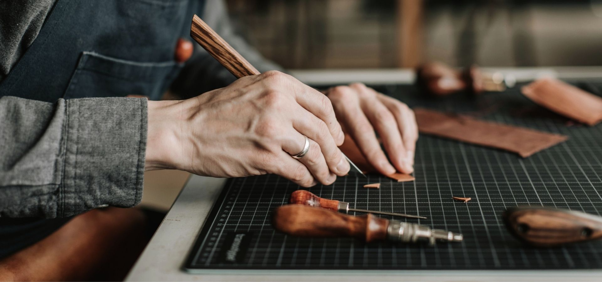 Craftsman using a precision tool to cut leather for a handmade leather craft item