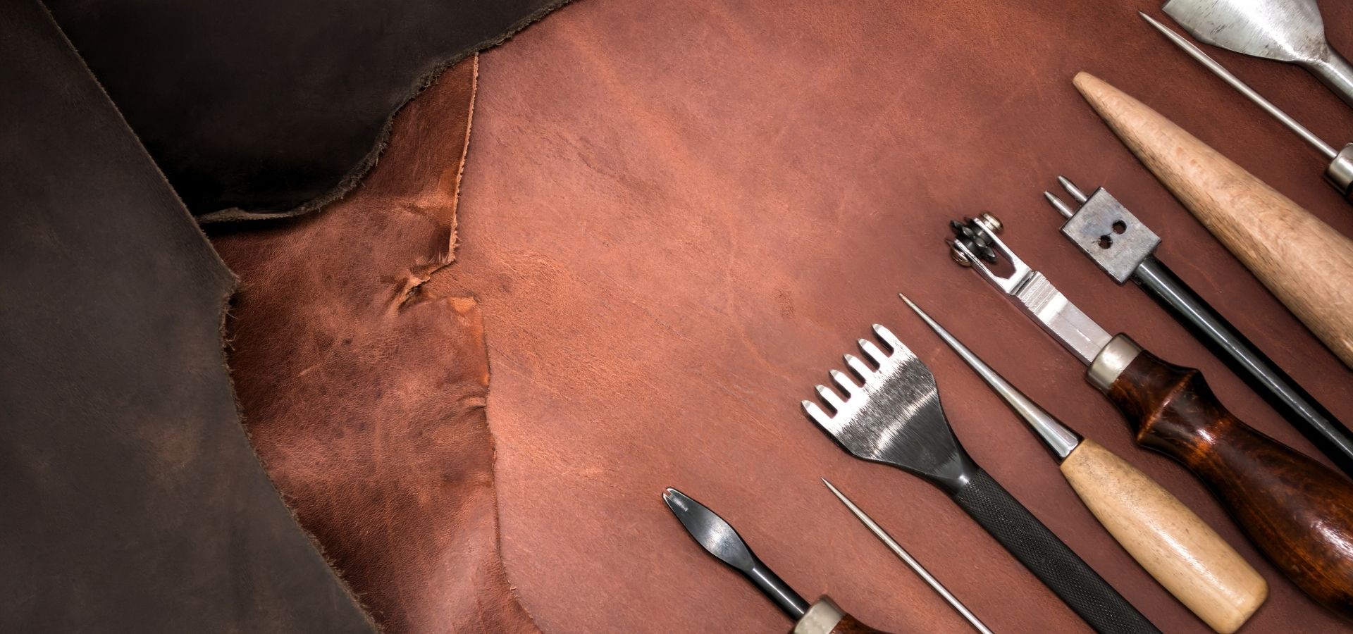 Close-up of raw leather and tools laid out for a leather craft workshop