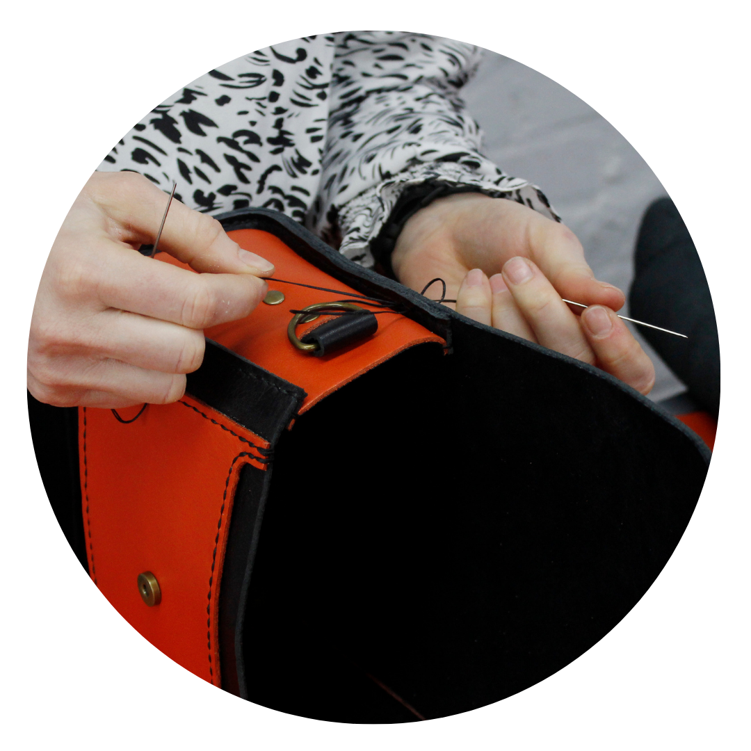 Close-up of hand-stitching technique used in leather craft to assemble a handmade leather bag