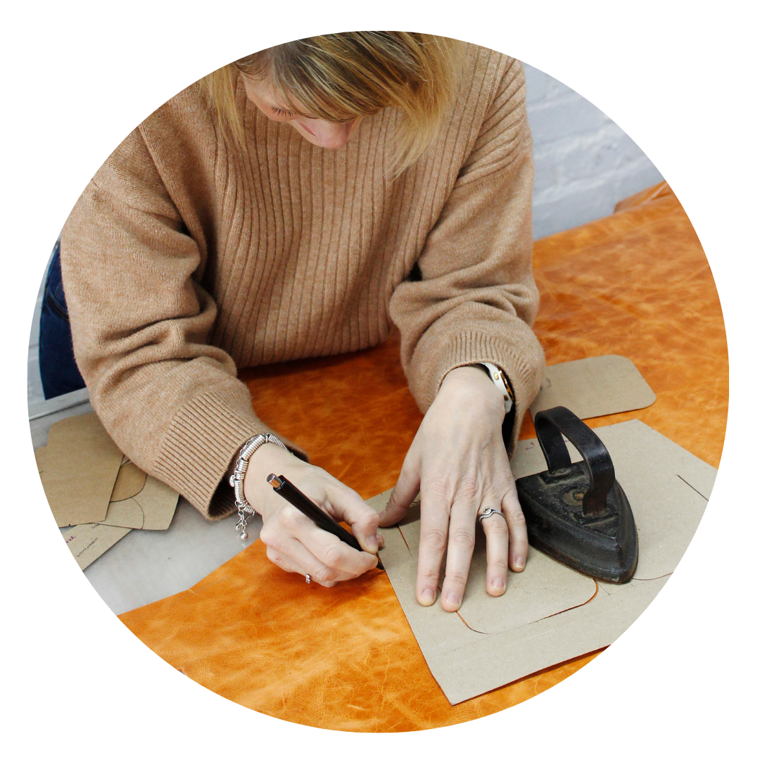 Woman tracing patterns on leather material as part of a leather craft workshop