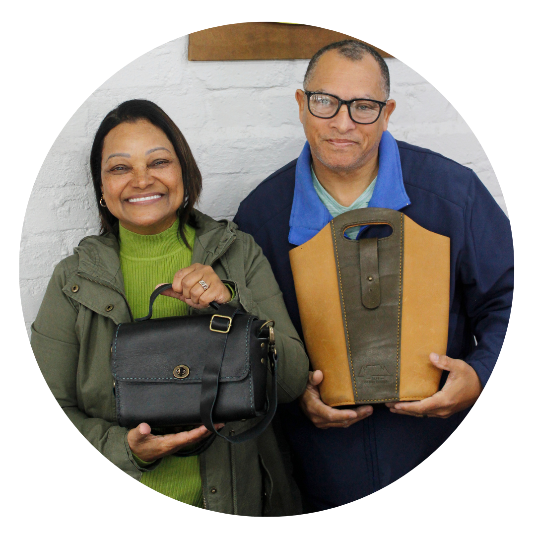 Two workshop participants holding their completed leather craft bags at Cape Leather Training